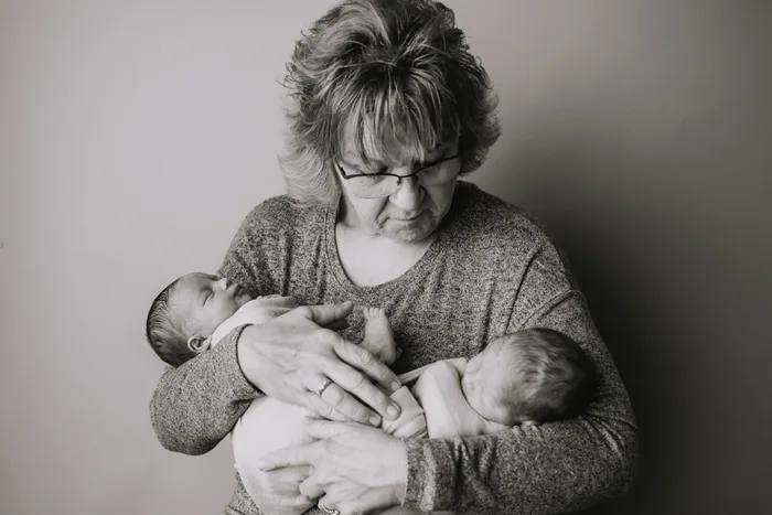 A grandmother tenderly holding sleeping newborn twins