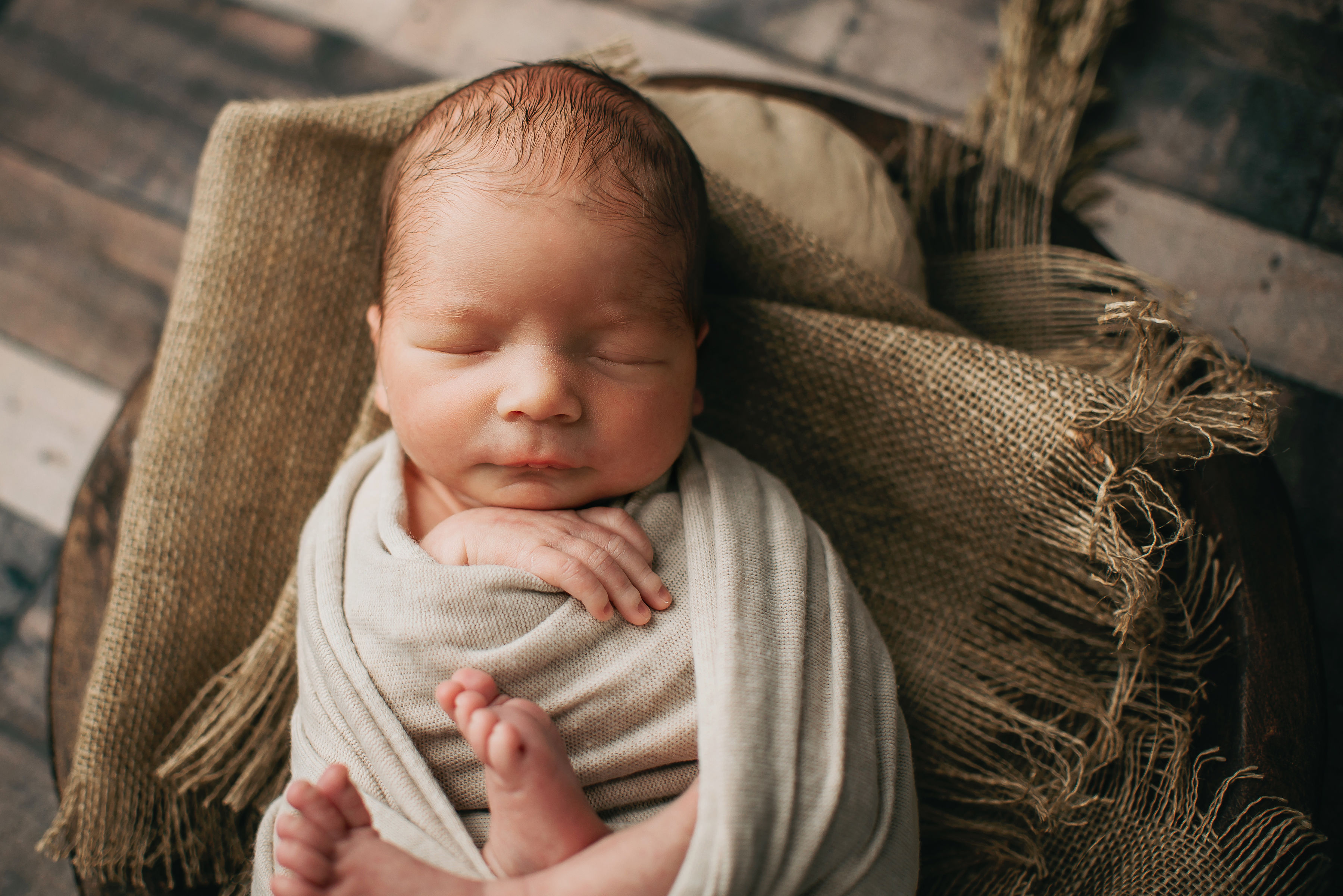 Newborn baby sleeping soundly, swaddled and curled up